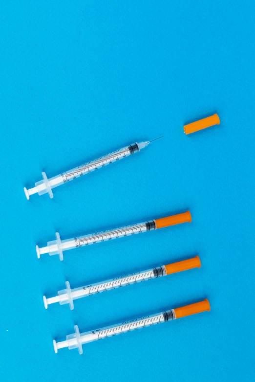 a row of sylls sitting on top of a blue surface, an illustration of, unsplash, syringe, cyan and orange, taken in the late 2000s, smoker