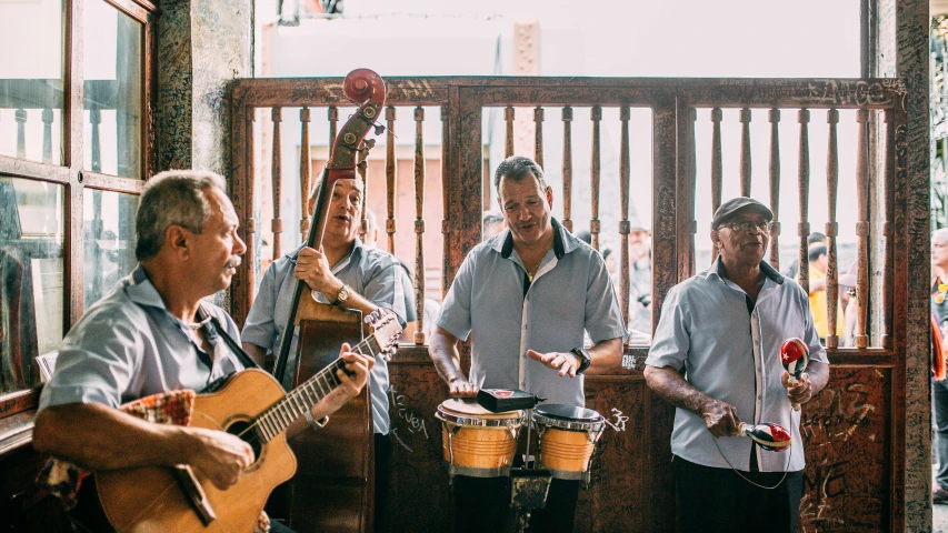 a group of men playing musical instruments in a room, an album cover, by Ceferí Olivé, unsplash, square, tourist destination, holding maracas, al fresco