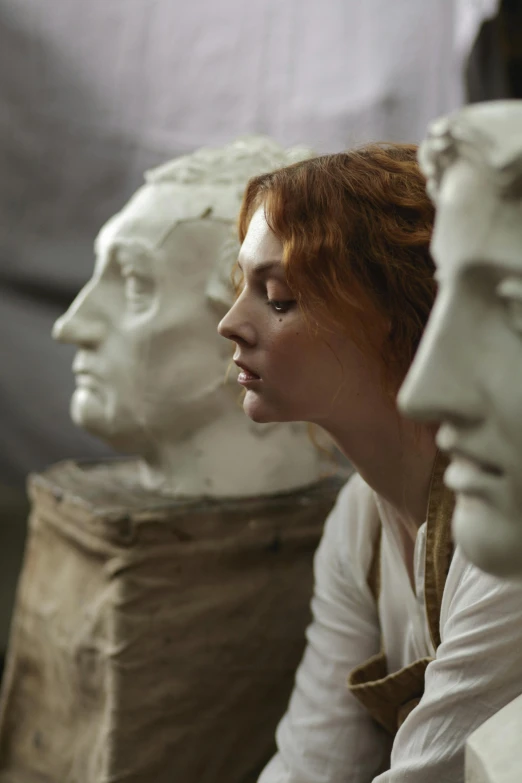 a woman sitting next to a group of statues, a marble sculpture, pre-raphaelitism, movie scene close up, sophia lillis, close - up profile face, behind the scenes