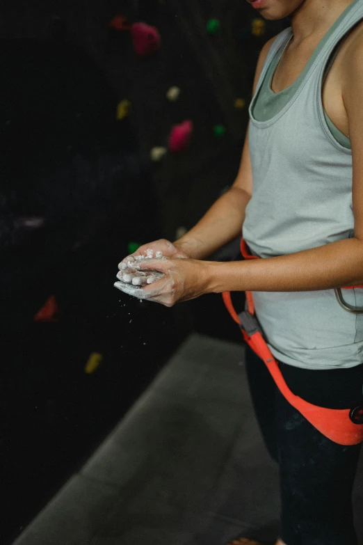 a woman standing in front of a climbing wall, partially cupping her hands, wash, accurate hands, webbing