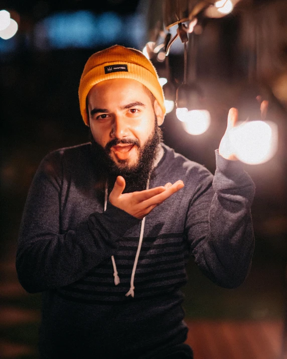a man with a beard wearing a yellow hat, pexels contest winner, bisexual lighting, shrugging, night outside, wearing beanie