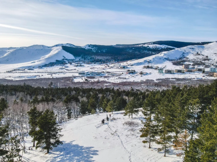 a group of people riding skis down a snow covered slope, by Muggur, pexels contest winner, les nabis, ground level view of soviet town, lush forest in valley below, фото девушка курит, mongol