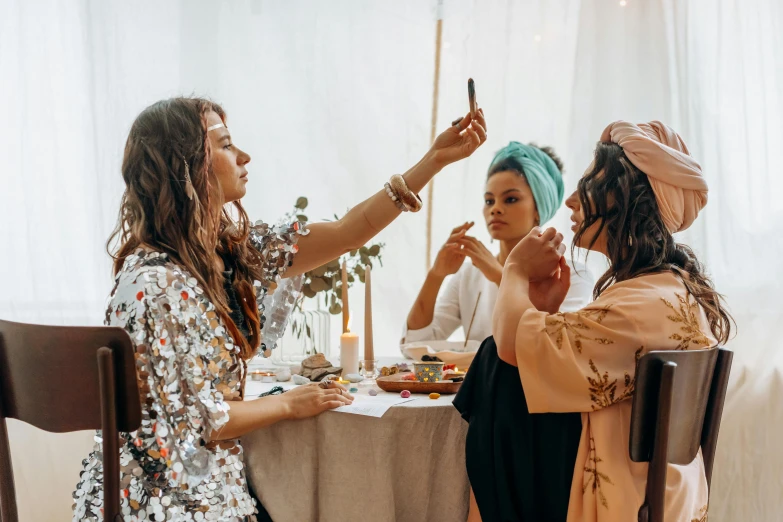 a group of women sitting around a table, a polaroid photo, by Julia Pishtar, trending on pexels, happening, putting makeup on, boho style, silk robes, profile image