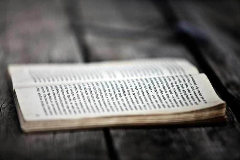 an open book sitting on top of a wooden table, unreadable text, realistic »