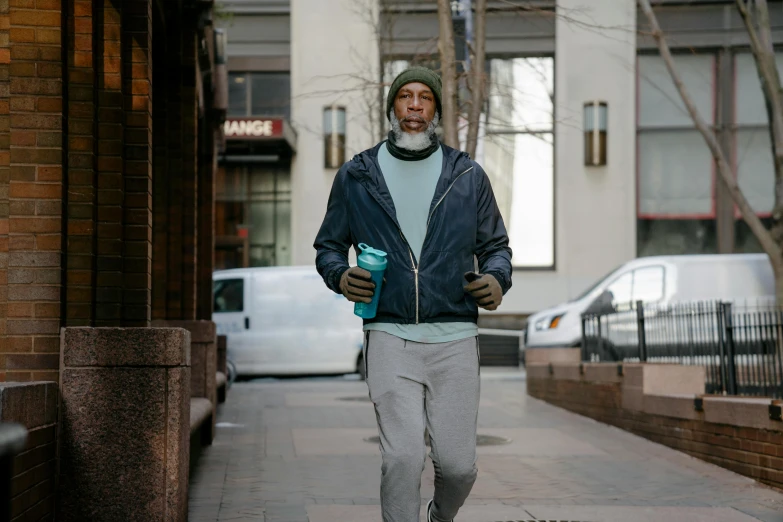 a man walking down a sidewalk with a cup of coffee, wearing teal beanie, lance reddick, reflective puffy coat, 5k