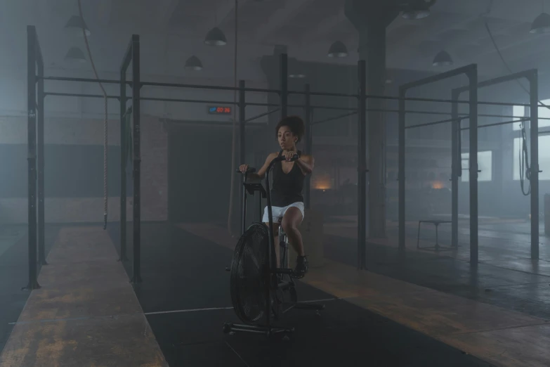 a woman riding a bike in a dark room, dingy gym, hyperrealistic vfx render, ashteroth, b - roll