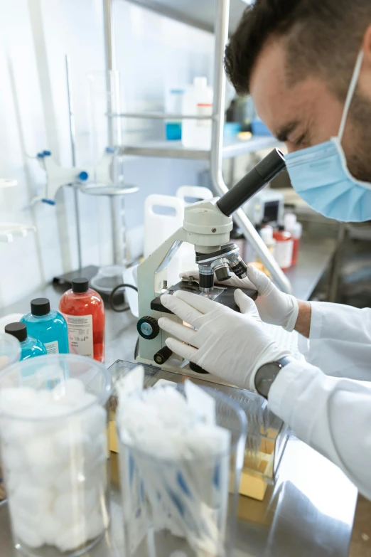 a man in a lab coat looking through a microscope, a microscopic photo, shutterstock, surgical supplies, 15081959 21121991 01012000 4k, instagram photo, in a research facility