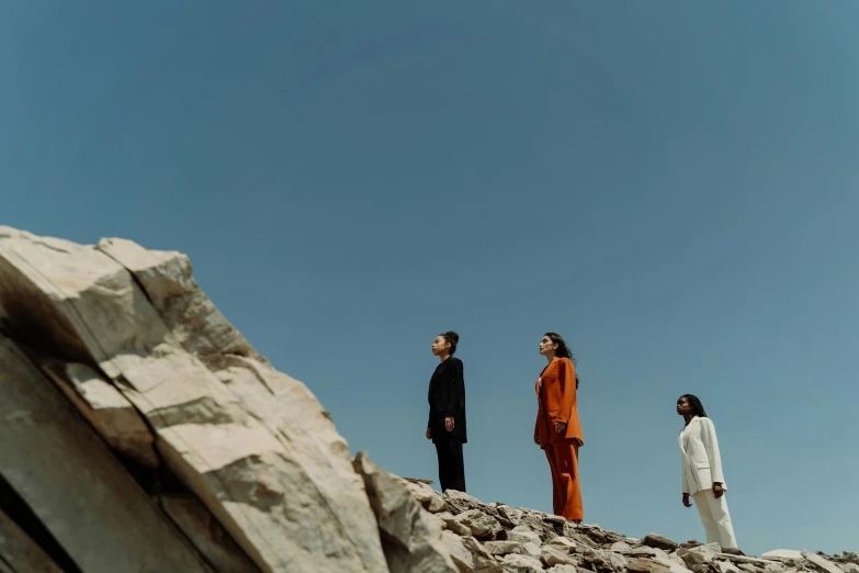 a group of people standing on top of a rocky hill, an album cover, by Emma Andijewska, pexels contest winner, bauhaus, elegantly dressed, three body problem, low angle facing sky, profile image