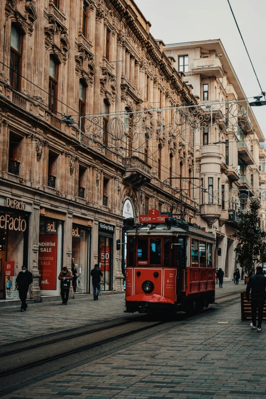 a red trolley traveling down a street next to tall buildings, a colorized photo, pexels contest winner, turkey, beige, 🚿🗝📝, profile image