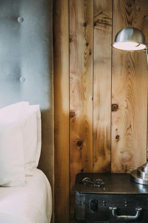 a suitcase sitting on top of a bed next to a lamp, inspired by Sarah Lucas, unsplash, wood panel walls, closeup shot, dwell, reclaimed lumber