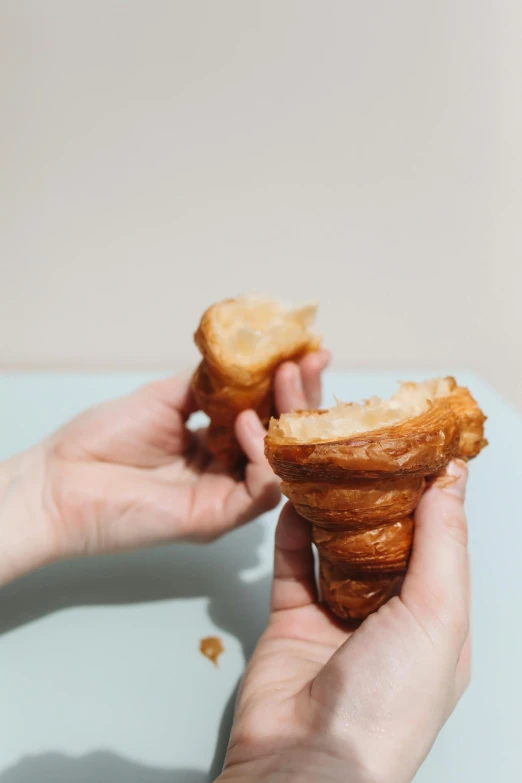 a person holding a pastry in their hand, by Andrée Ruellan, unsplash, photorealism, cone shaped, a pair of ribbed, gooey, ignant