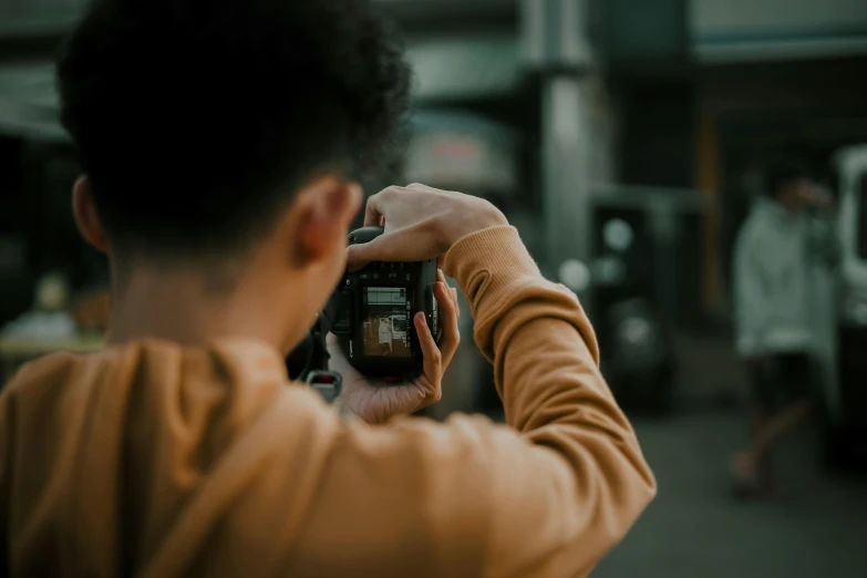 a person taking a picture with a camera, pexels contest winner, back towards camera, portrait pose, low quality footage, over his shoulder