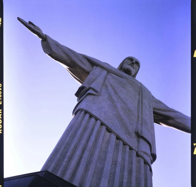 a statue of jesus stands in front of a blue sky, by Carey Morris, brazilian, lomography photo, up-angle view, olympics