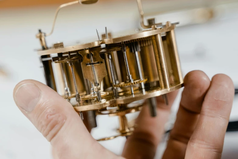 a close up of a person holding a small machine, an engraving, unsplash, kinetic art, clocks, scientific instruments, victor horta, multi-part