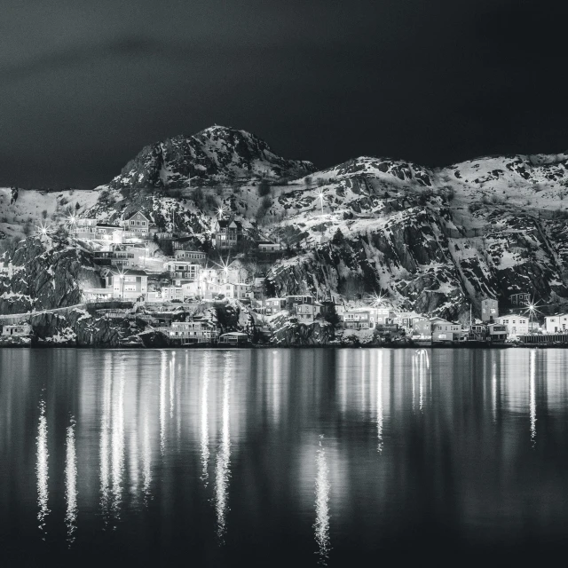 a black and white photo of a mountain range, a black and white photo, pexels contest winner, reflection of led lights, fjord, cold colours, winter night