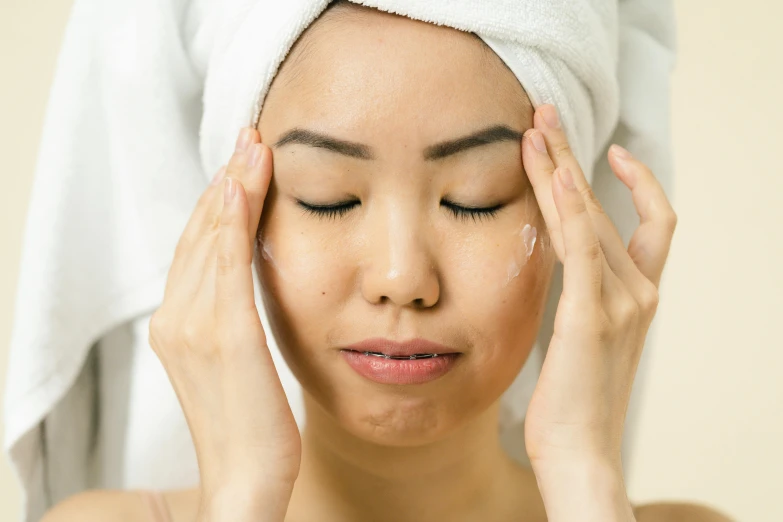 a woman with a towel wrapped around her head, shutterstock, mingei, hands on face, showing forehead, asian descent, square facial structure