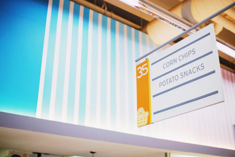 a sign hanging from the side of a building, inspired by Chippy, unsplash, food court in a mall, blue theme and yellow accents, crisps, 3 5 °