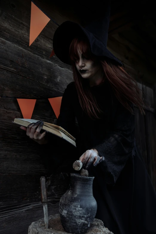 a woman dressed as a witch reading a book, pexels contest winner, brewing potion in witch hut, profile image, witchcore clothes, black