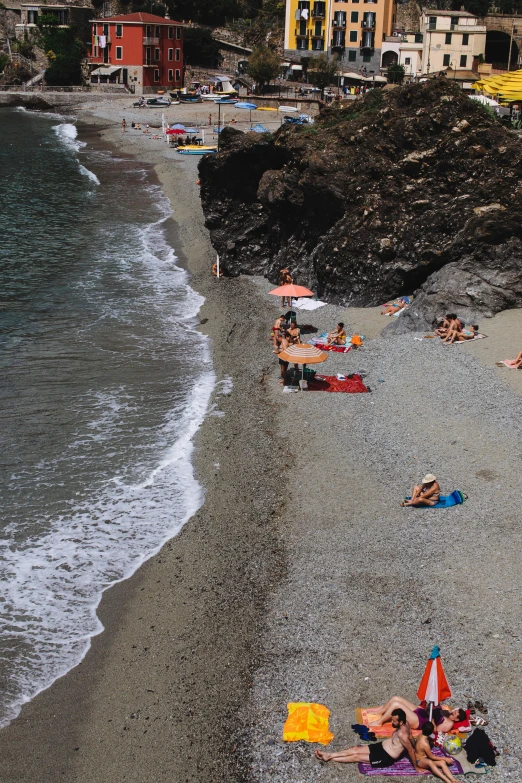 a group of people laying on top of a sandy beach, cinq terre, santorini, profile image