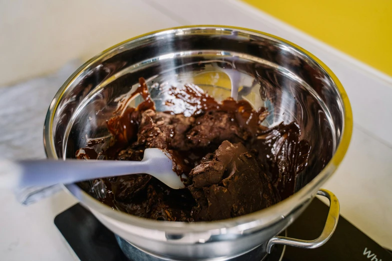 a pot filled with chocolate sitting on top of a stove, by Julia Pishtar, pexels, process art, gloss finish, ingredients on the table, middle close up, ready to eat