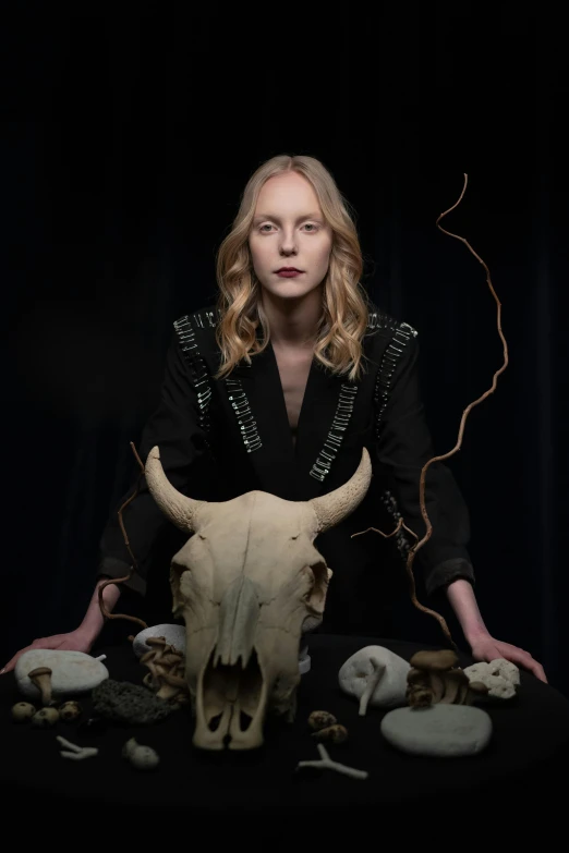 a woman sitting in front of a cow skull, inspired by Nína Tryggvadóttir, renaissance, press shot, skulls in hands, uma thurman, ram antlers