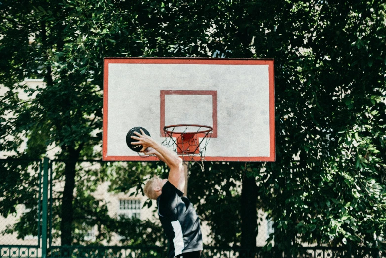 a man standing on top of a basketball court holding a basketball, by Carey Morris, pexels contest winner, dunking, at a park, andrzej marszalek, cardboard
