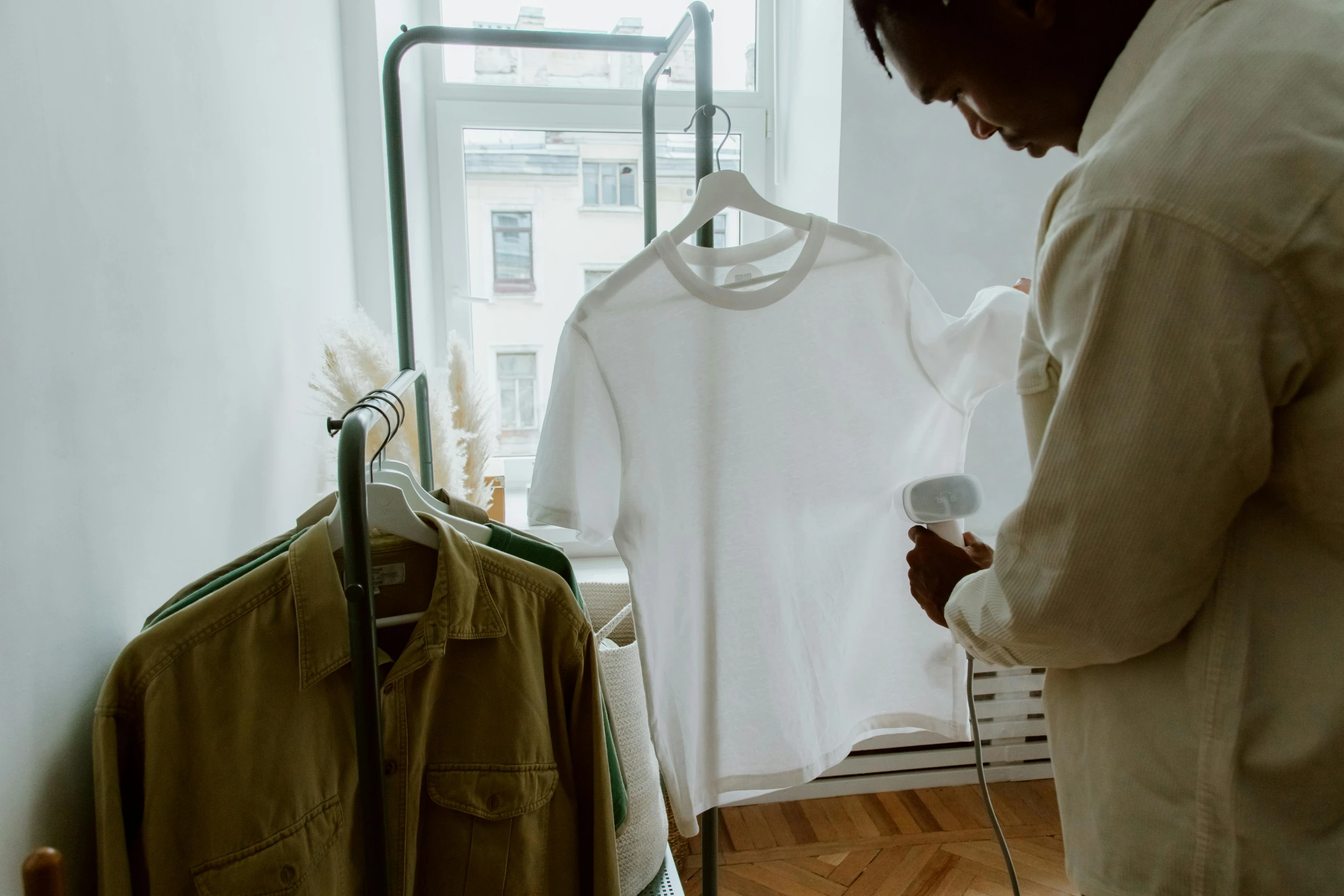 a man is looking at a t - shirt on a hanger, by Julia Pishtar, wearing white pajamas, top selection on unsplash, low quality footage, green and brown clothes