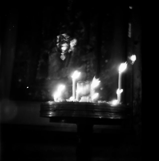 a group of lit candles sitting on top of a table, a black and white photo, by Kati Horna, holga 120n, in orthodox church, concert photo, photo taken on an old box camera