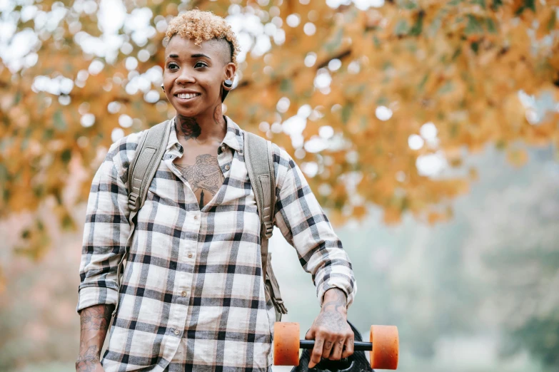 a close up of a person holding a skateboard, a portrait, by Lena Alexander, trending on pexels, wearing plaid shirt, with a backpack, african american woman, during autumn