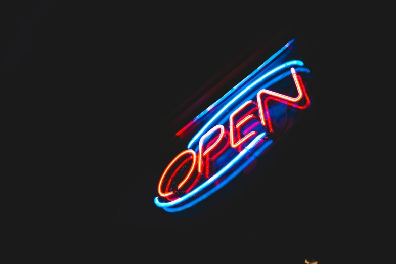 a neon sign on the side of a building, by Alexander Bogen, pexels, open shiny floor, blue and red, opening, operation