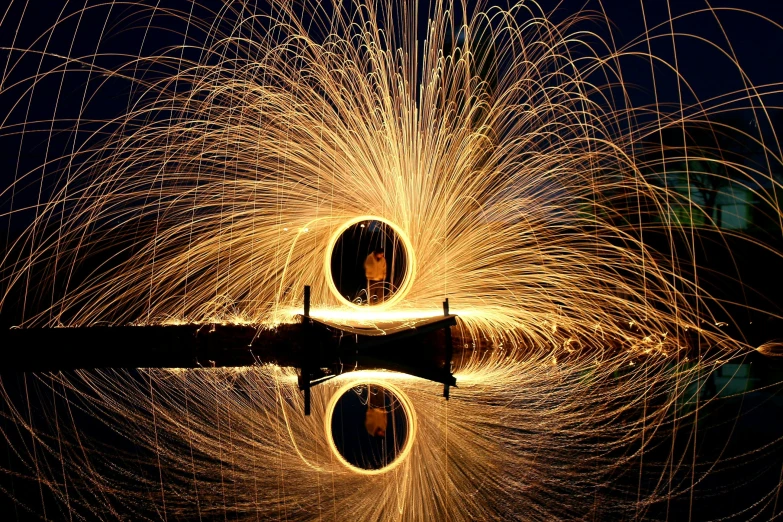 a fire spinning in the air next to a body of water, by Jan Rustem, pexels contest winner, large electrical gold sparks, portal to another world, award - winning photo. ”