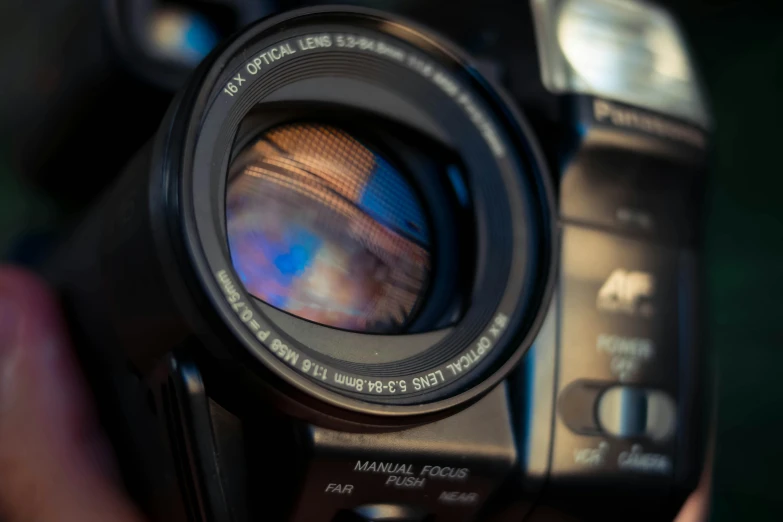 a close up of a person holding a camera, a picture, facing the camera, anamorphic lens, lens glare, face in focus