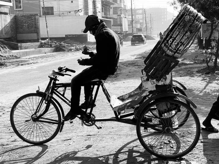 a man riding a bike with a basket on the back of it, a black and white photo, by Odhise Paskali, flickr, with a wooden stuff, mobile, working, kyza saleem