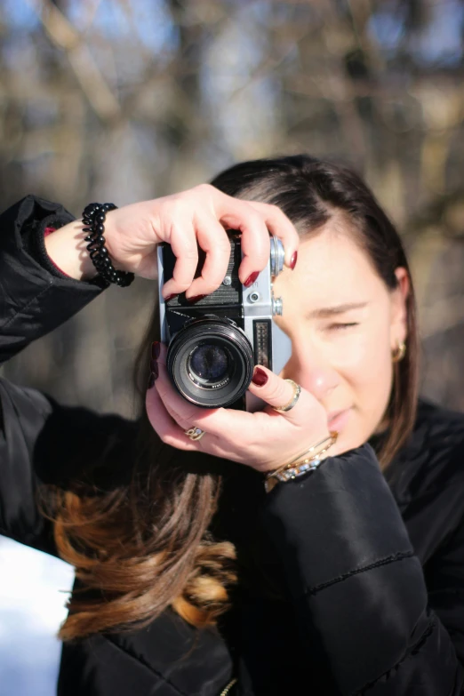 a woman taking a picture with a camera, looking down on the camera, professional photo-n 3, low colour, outdoors
