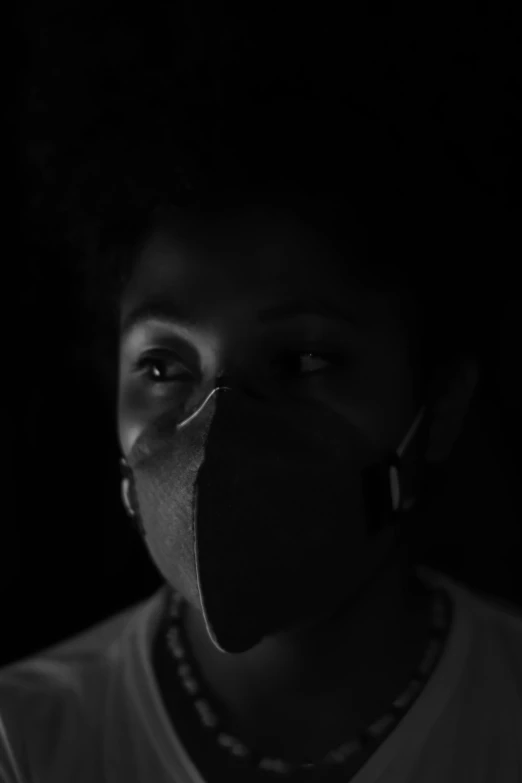a person wearing a face mask in the dark, a black and white photo, inspired by Carrie Mae Weems, ashteroth, looking to the camera, avatar image, people are wearing masks