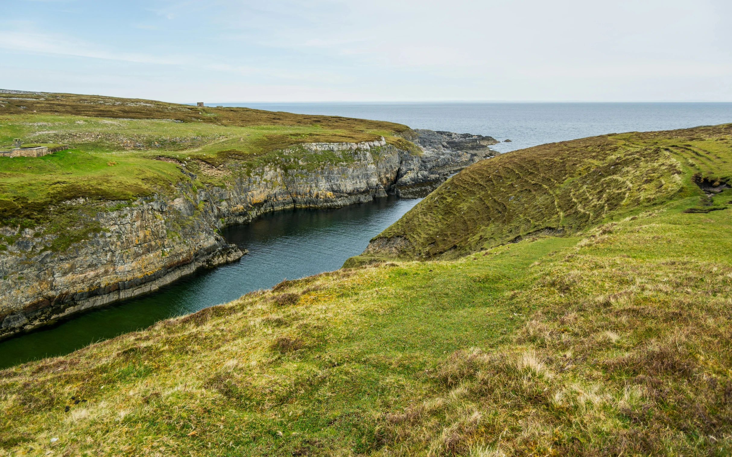 a body of water sitting on top of a lush green hillside, by John Murdoch, pexels contest winner, les nabis, atlantic puffin, deep sinkhole, thumbnail, high quality photo