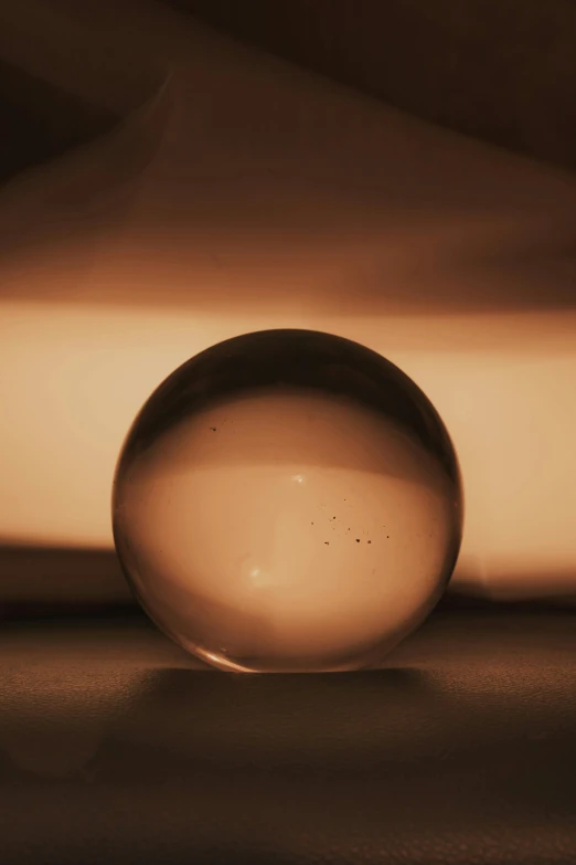 a glass ball sitting on top of a table, a picture, by Greg Rutkowski, unsplash, light and space, gradient brown to white, quartz, ignant, sepia