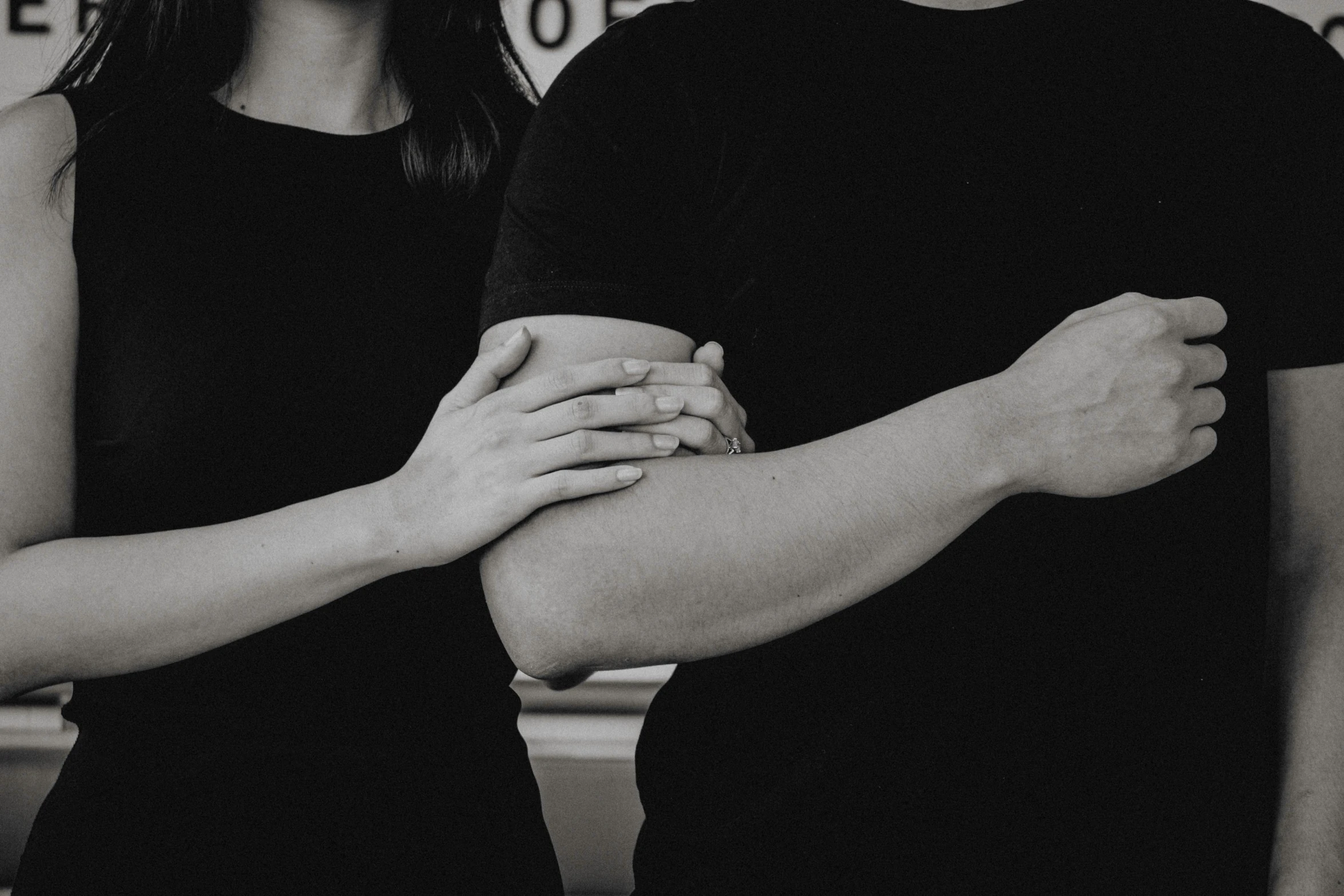 a man and a woman standing next to each other, a black and white photo, unsplash, symbolism, closeup of arms, wearing a black shirt, background image, four hands