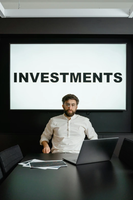 a man sitting at a table with a laptop in front of him, a portrait, trending on unsplash, incoherents, wealth, large commercial led screens, a person standing in front of a, in a classroom