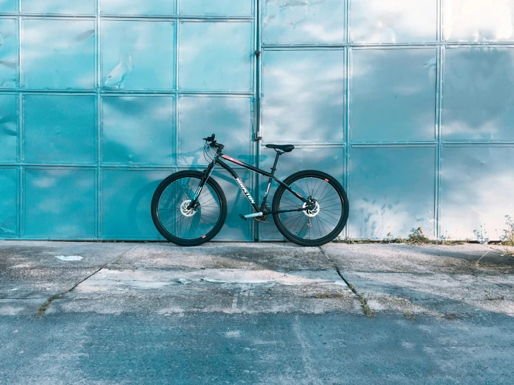 a bicycle leaning against a blue wall, pexels contest winner, realism, background image, stainless steel, profile pic, on the concrete ground