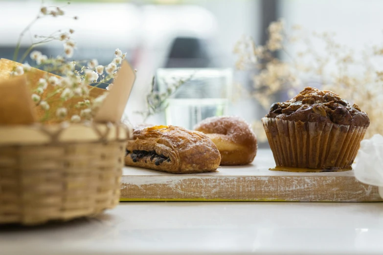 a couple of muffins sitting on top of a wooden cutting board, unsplash, overflowing feast buffet table, windowsill, daily specials, botanicals