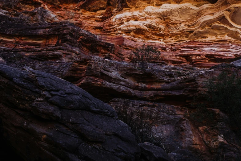 a person riding a horse through a canyon, an album cover, by Lee Loughridge, unsplash contest winner, australian tonalism, crazy looking rocks, striations, black and terracotta, ((rocks))