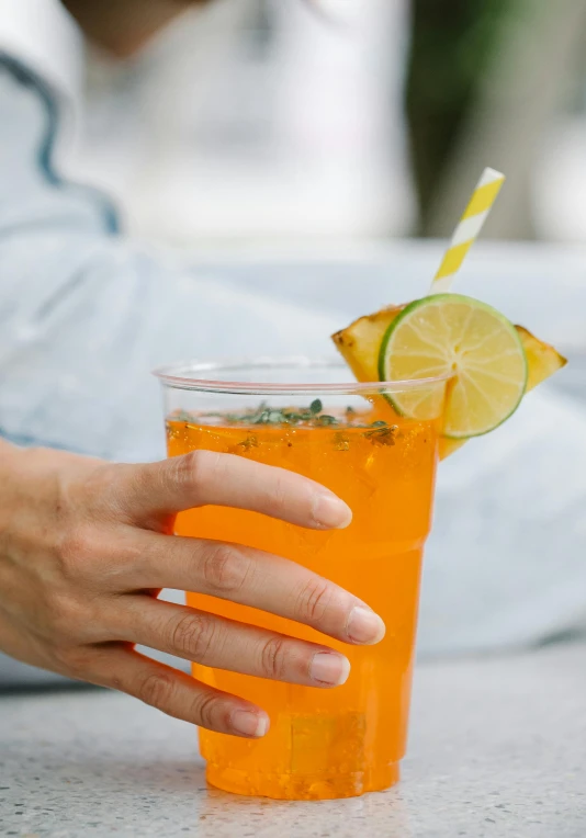 a close up of a person holding a drink, yellow-orange, oceanside, square, not cropped