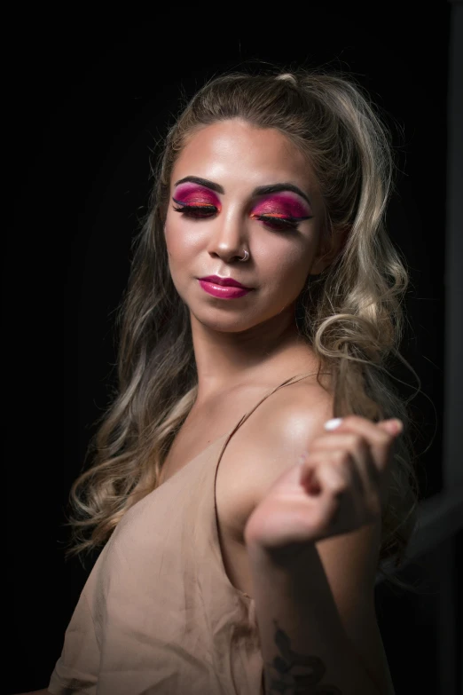 a woman with pink makeup posing for a picture, dark backdrop, hands behind her pose!, looking off into the distance, bisexual lighting