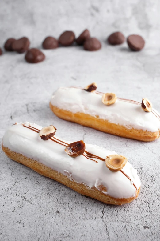 a couple of doughnuts sitting on top of a table, with a long white, white with gold accents, naudline pierre, slim