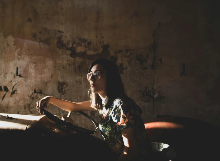 a woman sitting on a couch in a dark room, inspired by Elsa Bleda, pexels contest winner, driving a hotrod, girl wearing round glasses, kiko mizuhara, sun overhead