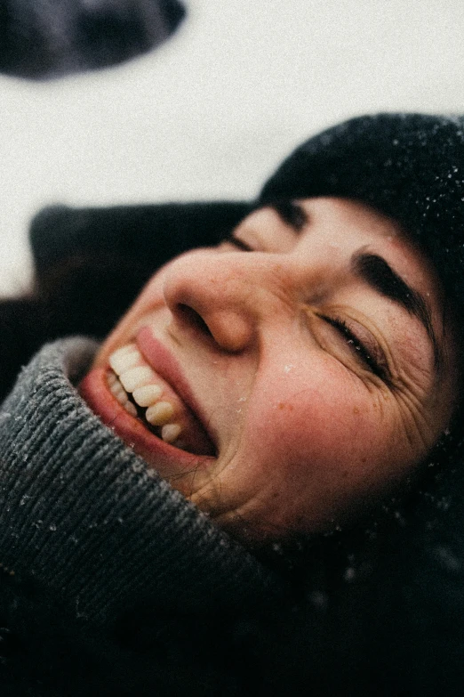 a woman laying on top of a snow covered ground, pexels contest winner, clenching teeth, detailed glad face, beanie, it's raining outside