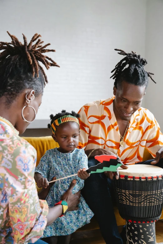 a group of people sitting on a couch playing drums, by Arabella Rankin, pexels contest winner, black arts movement, portrait of family of three, holding maracas, chief keef, toddler