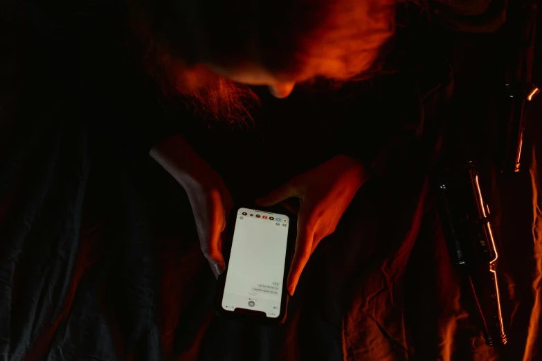 a man looking at his cell phone in the dark, pexels, a portrait of a suicidal girl, glowing red, slightly pixelated, holding it out to the camera