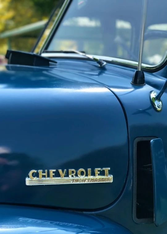 a close up of the hood of a blue truck, an album cover, by Kev Walker, trending on unsplash, the car is corvette c2 1969, vintage colours 1 9 5 0 s, profile image, golden detailing